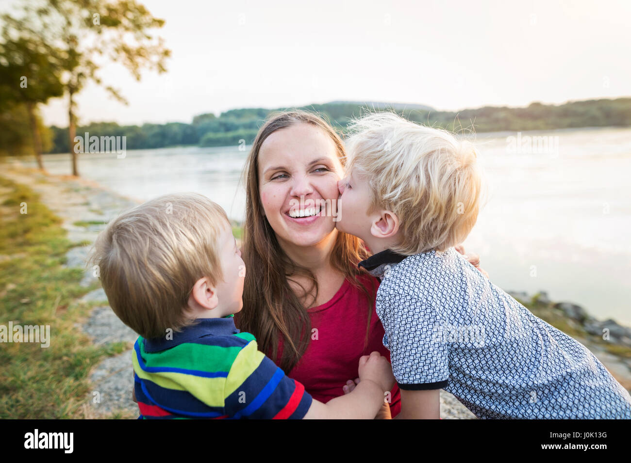 Mother with two sons at the lake, sunny spring day. Stock Photo