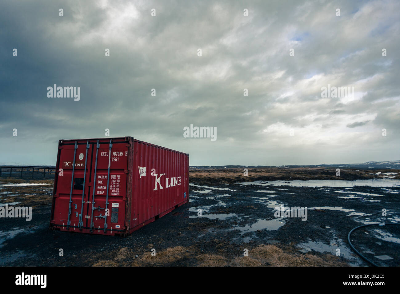 A red shipping container abandoned on a waterlogged field near Reykjavik, Iceland Stock Photo