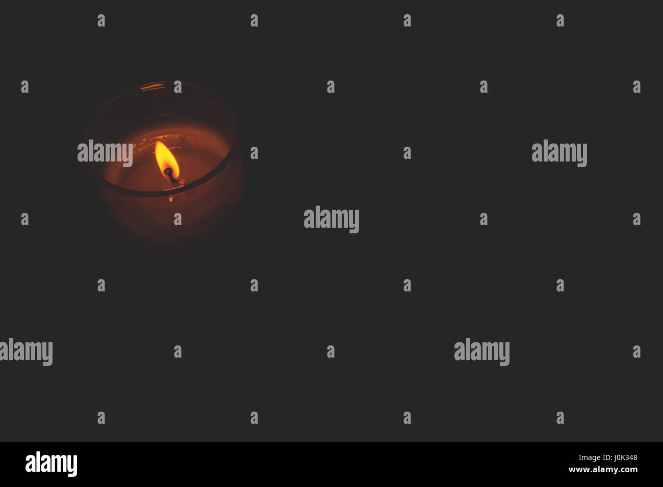 Candle burning in the dark. Closeup, beautiful orange flame Stock