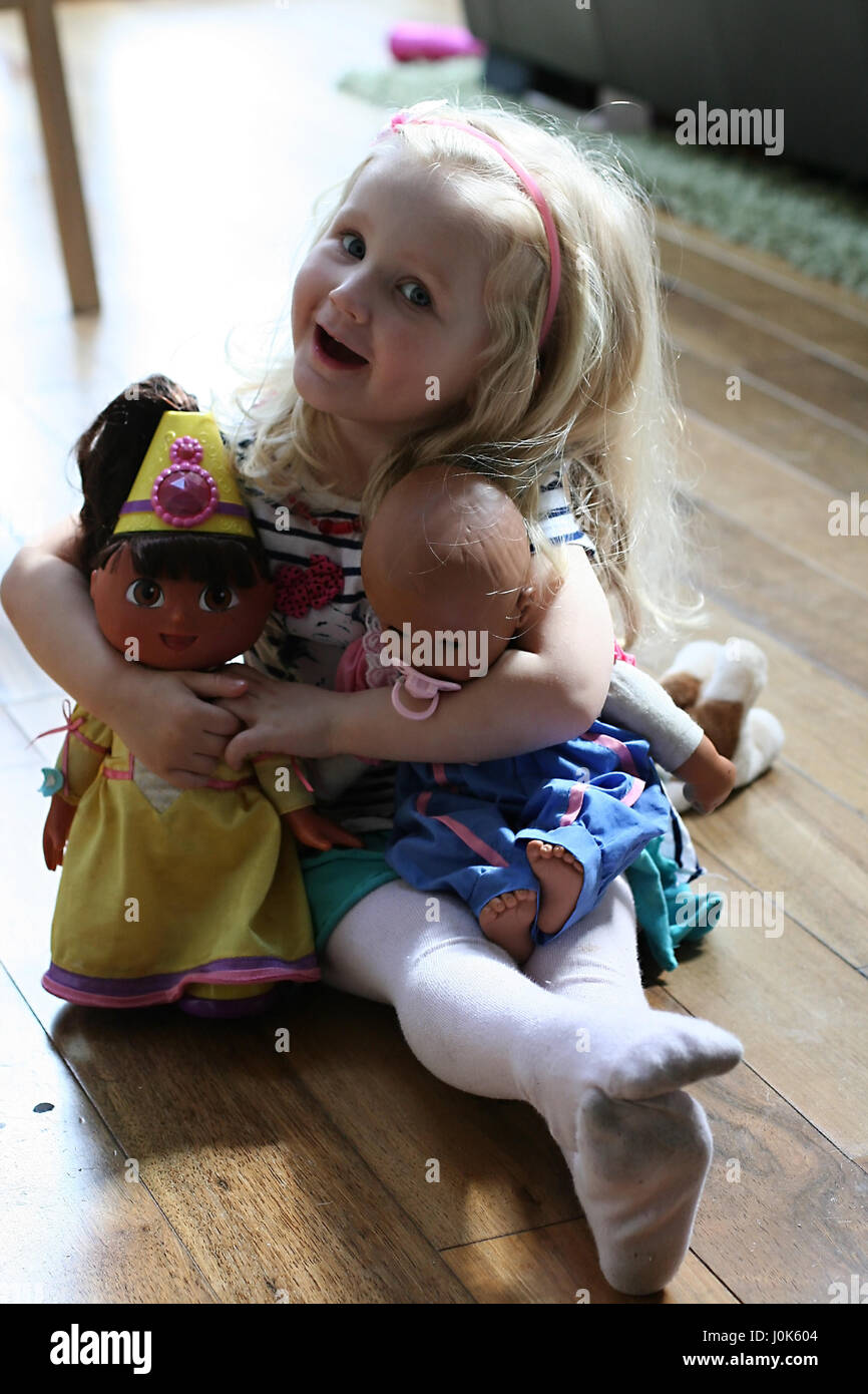 Little blonde girl, child playing with her dolls, Dora the explorer, Annabel, children toys, kid toys Stock Photo