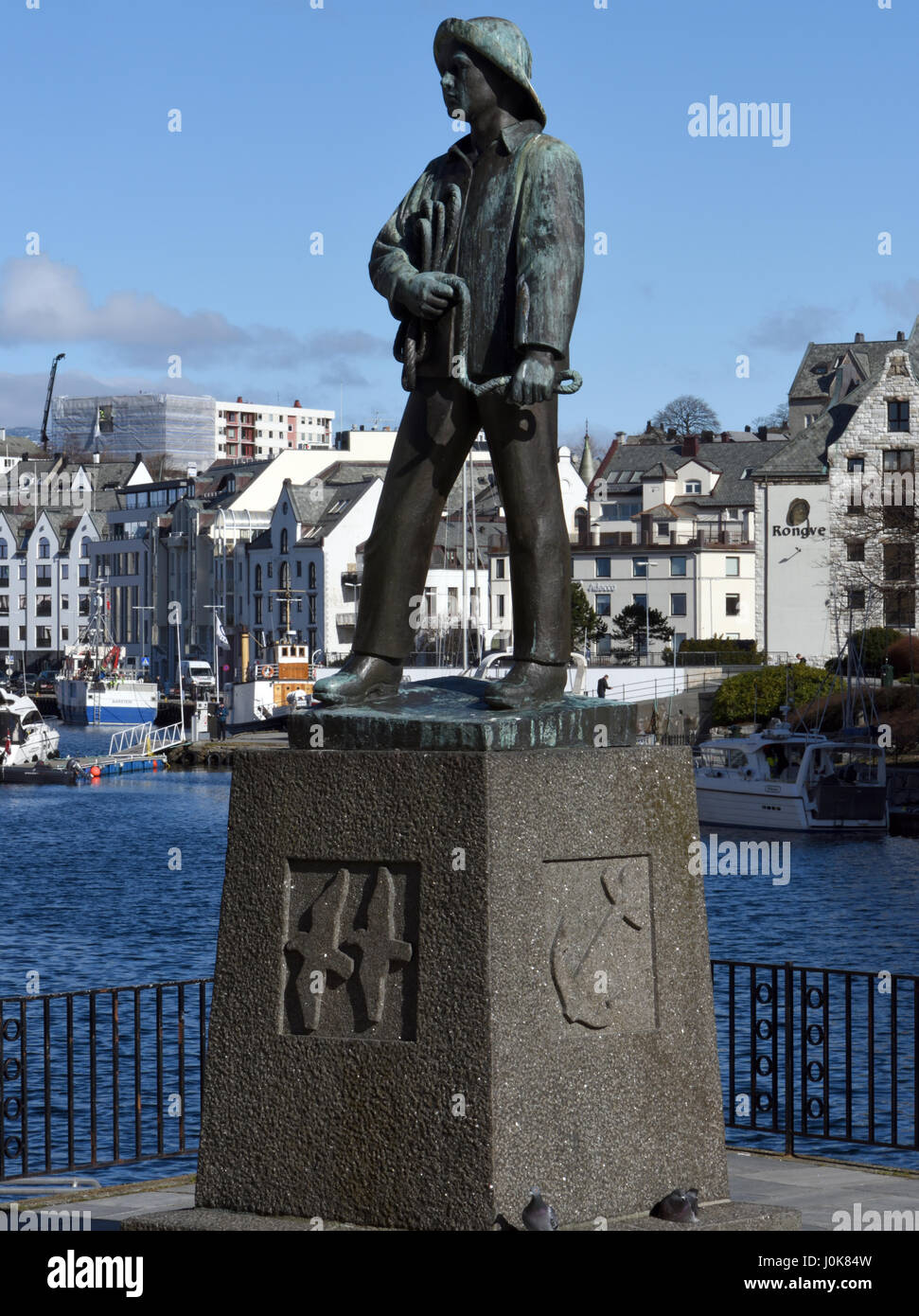 A statue on the waterfront of the harbour at  Alesund. The statue represents a young fisherman: Skårungen, the fisher boy    Ålesund, Møre og Romsdal, Stock Photo