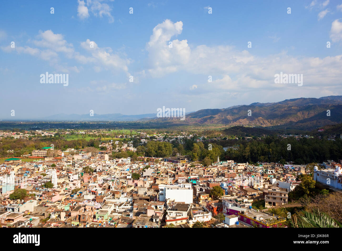 a scenic aerial view of nalagarh city in north india with mountains trees and colorful buildings under a blue cloudy sky in springtime Stock Photo