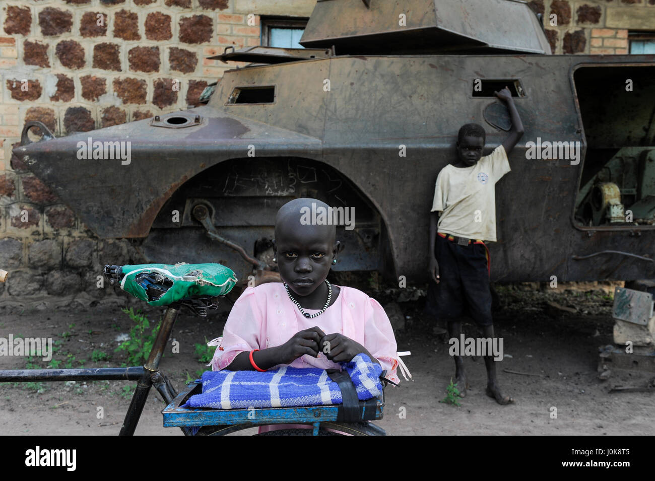 SOUTH SUDAN, Lakes State, town Rumbek, abandoned wreck of armoured personnel wagon Cadillac Gage V-150 Commando, Made in USA, from second sudanese civil war between south sudanese peoples liberation army SPLA and Sudanese Armed Forces SAF at former SAF barracks, girl with bicycle Stock Photo