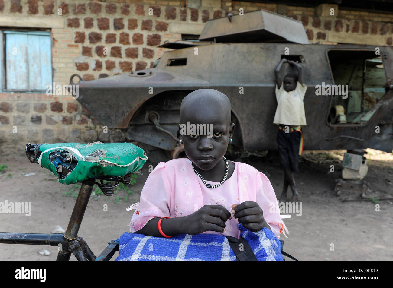 SOUTH SUDAN, Lakes State, town Rumbek, abandoned wreck of armoured personnel wagon Cadillac Gage V-150 Commando, Made in USA, from second sudanese civil war between south sudanese peoples liberation army SPLA and Sudanese Armed Forces SAF at former SAF barracks, girl with bicycle Stock Photo