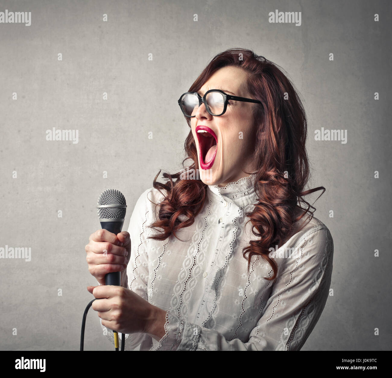 Woman singing with microphone Stock Photo