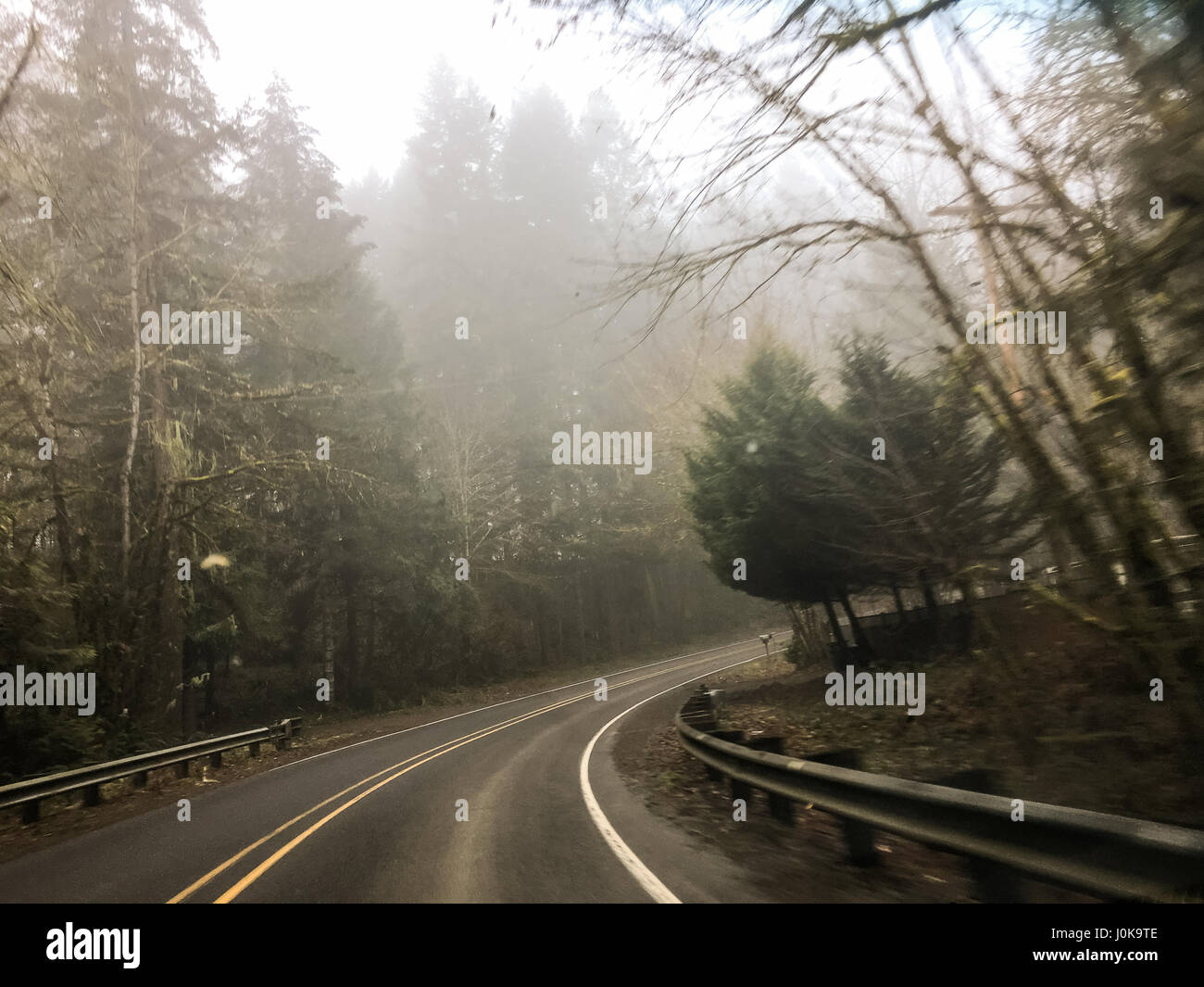 Right turn with rain coming down and fog in the air on this country highway road in Oregon. Stock Photo