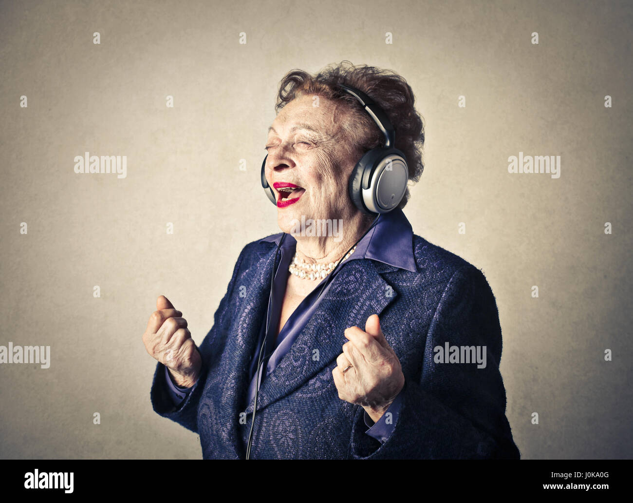 Old woman singing while listening to music Stock Photo