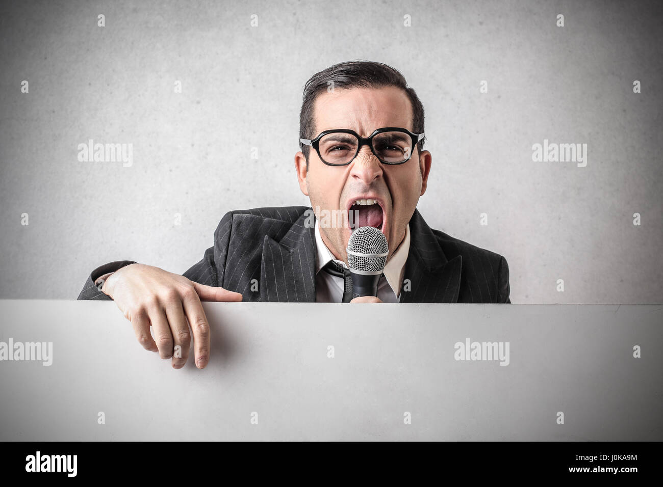 Businessman with microphone yelling Stock Photo - Alamy