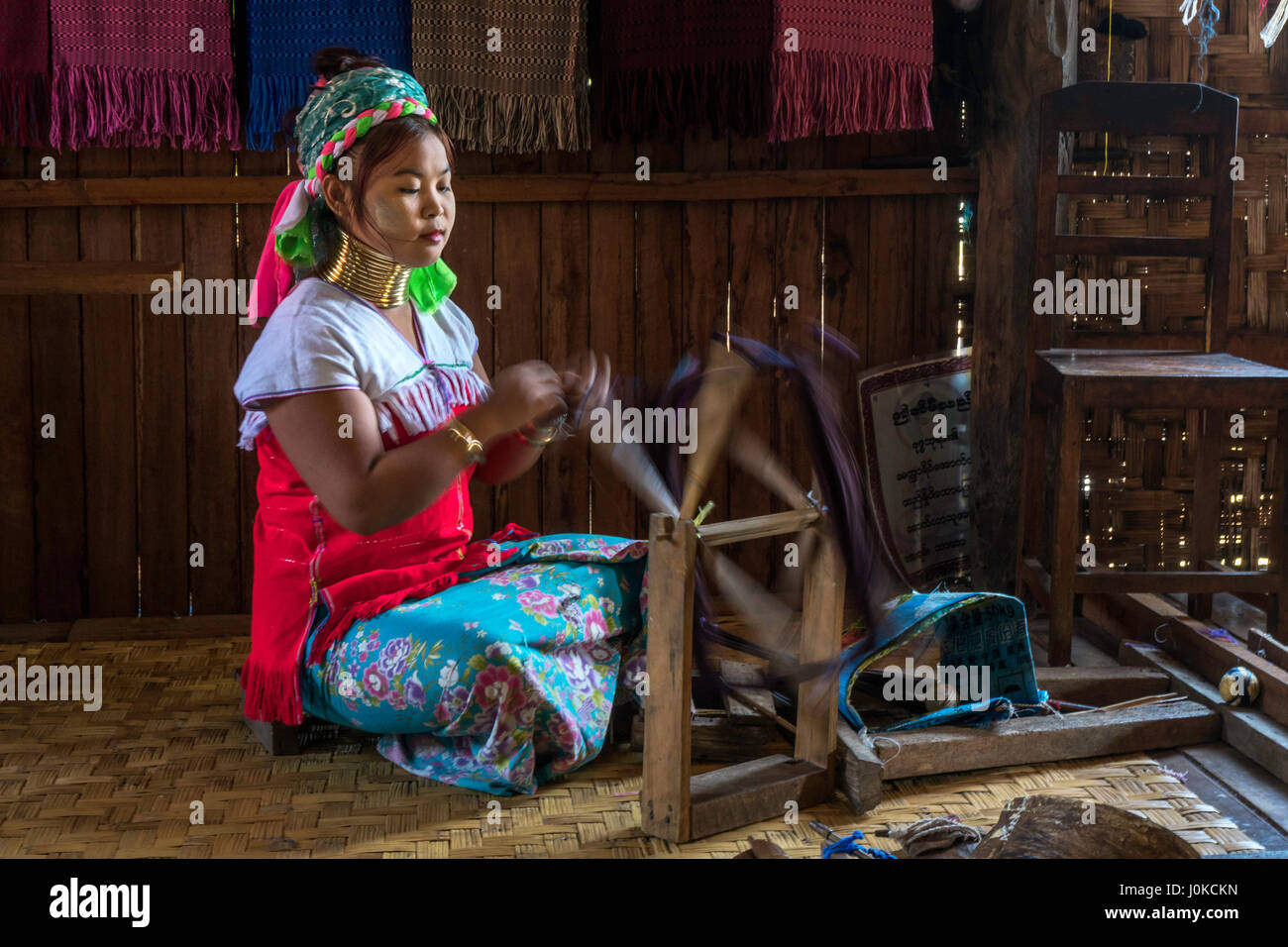 Girl from the Kayan tribe spinning thread for their handwoven cloth at Inle lake, Shan state, Myanmar Stock Photo