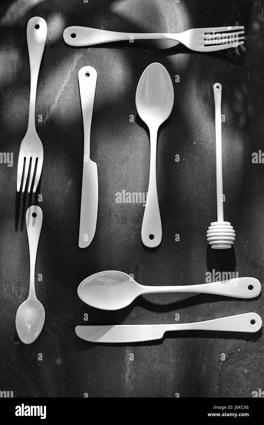 White enamel cutlery on black surface Stock Photo - Alamy