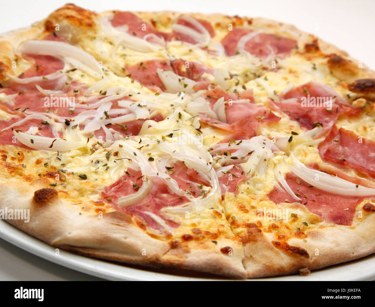 Delicious fresh pizza with ham and onions on white background. Selective focus, shallow DOF Stock Photo
