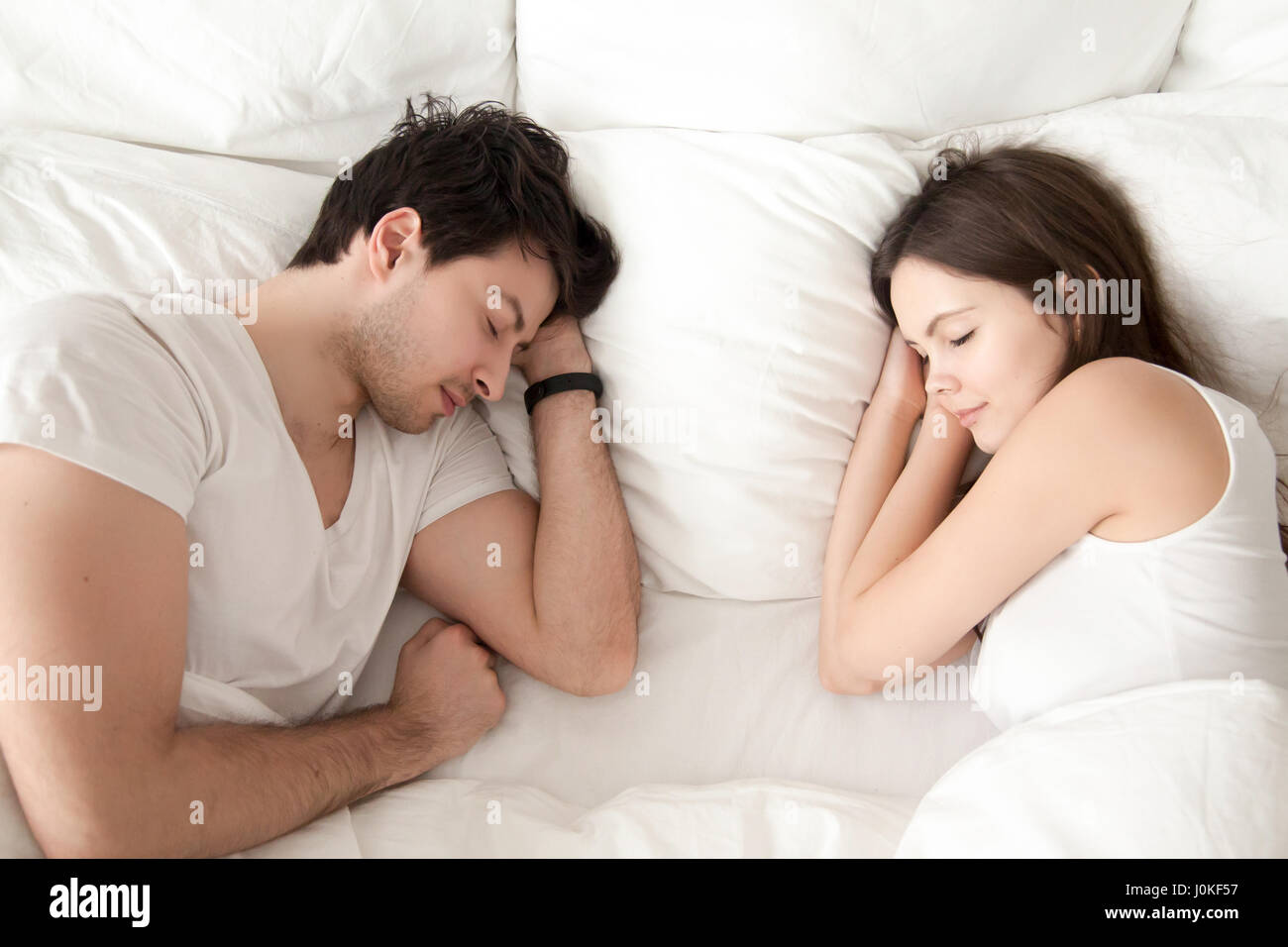 Happy young couple sleeping together in bed, enjoying sweet drea Stock Photo