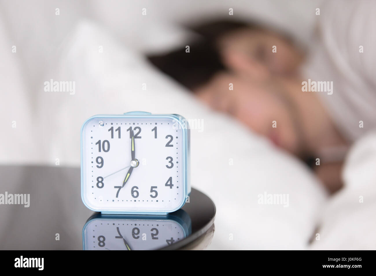 Young couple sleeping in bed next to an alarm clock Stock Photo