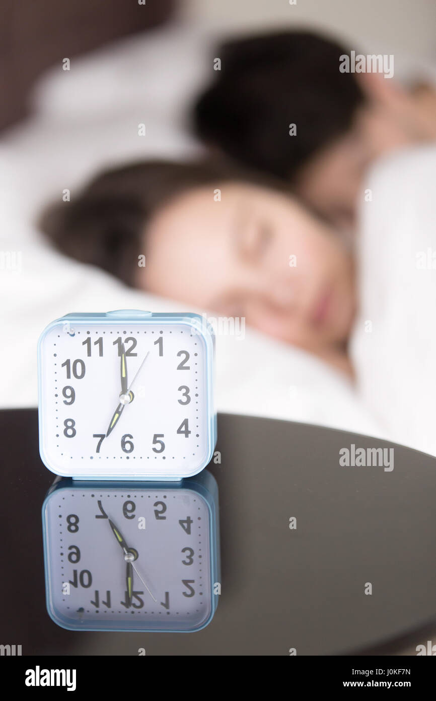 Alarm clock and couple asleep early in the morning, vertical Stock Photo