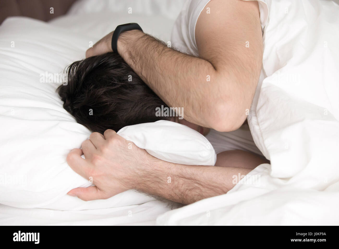 Man covering head with hands in bed, wakeup or depression Stock Photo