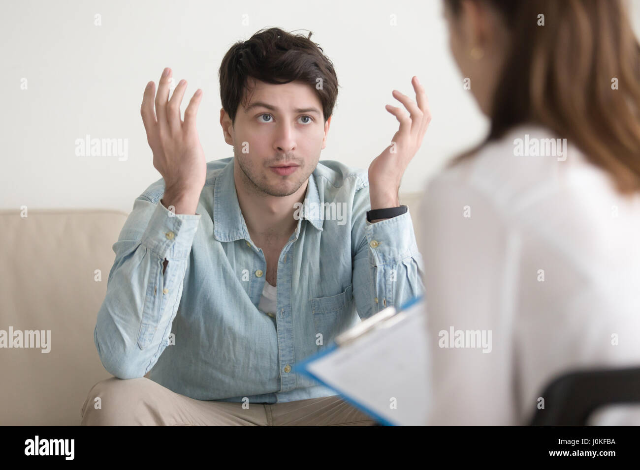 Young male patient talking about his problem to female psychothe Stock Photo