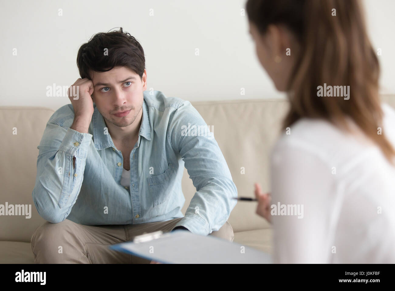 Serious guy listening to female psychologue, diagnosis or doctor Stock Photo