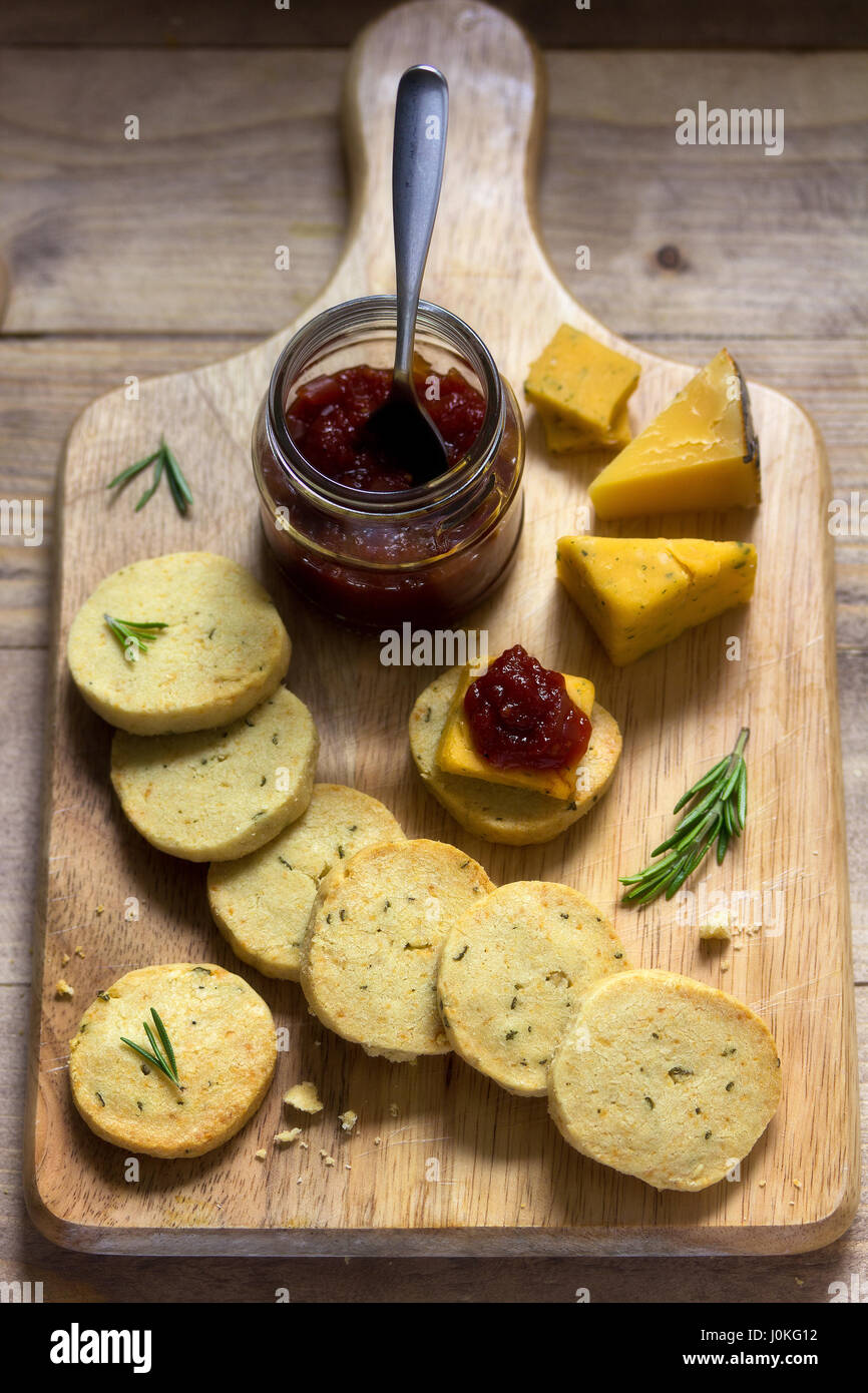 Rosemary crackers with cheddar cheese on board with sweet tomato relish