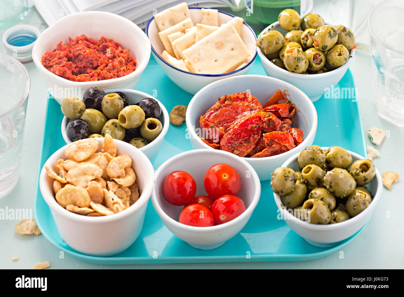 Spanish tapas on blue tray - red pesto, olives, cherry tomatoes, red pesto,  crackers Stock Photo - Alamy