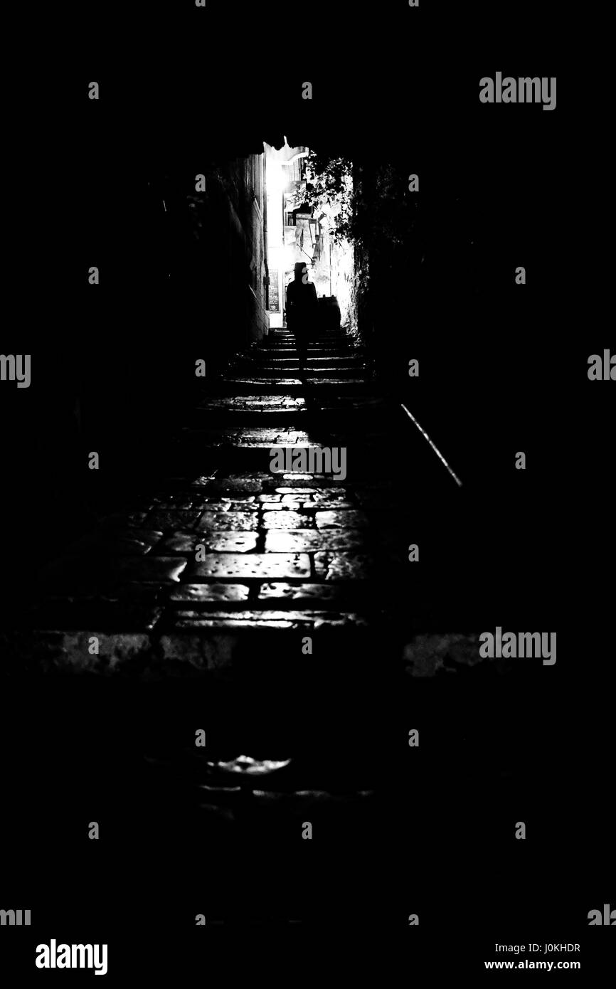 Woman in Hat walks through allyway at Night, Croatia Stock Photo