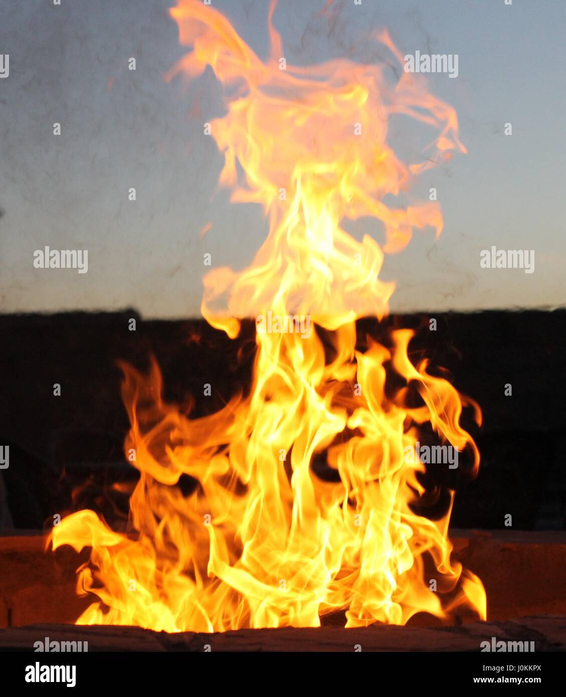 Fire with sunset in background Stock Photo - Alamy