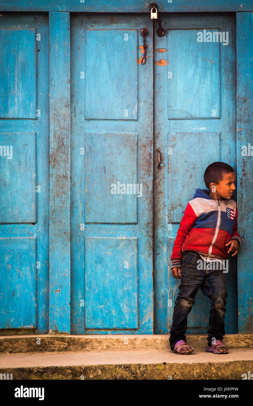 A young boy watches his friends play football in a small village in