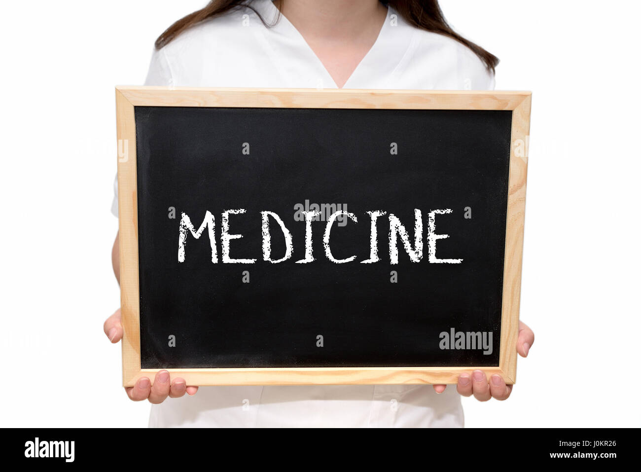 Female nurse holding a slate board with the text Medicine written with chalk, isolated on white background. Stock Photo