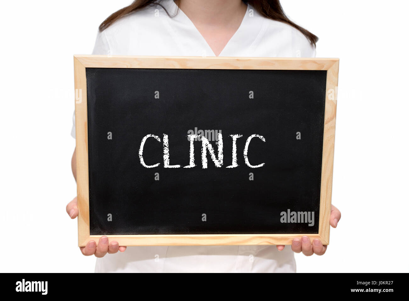 Female nurse holding a slate board with the text Clinic written with chalk, isolated on white background. Stock Photo