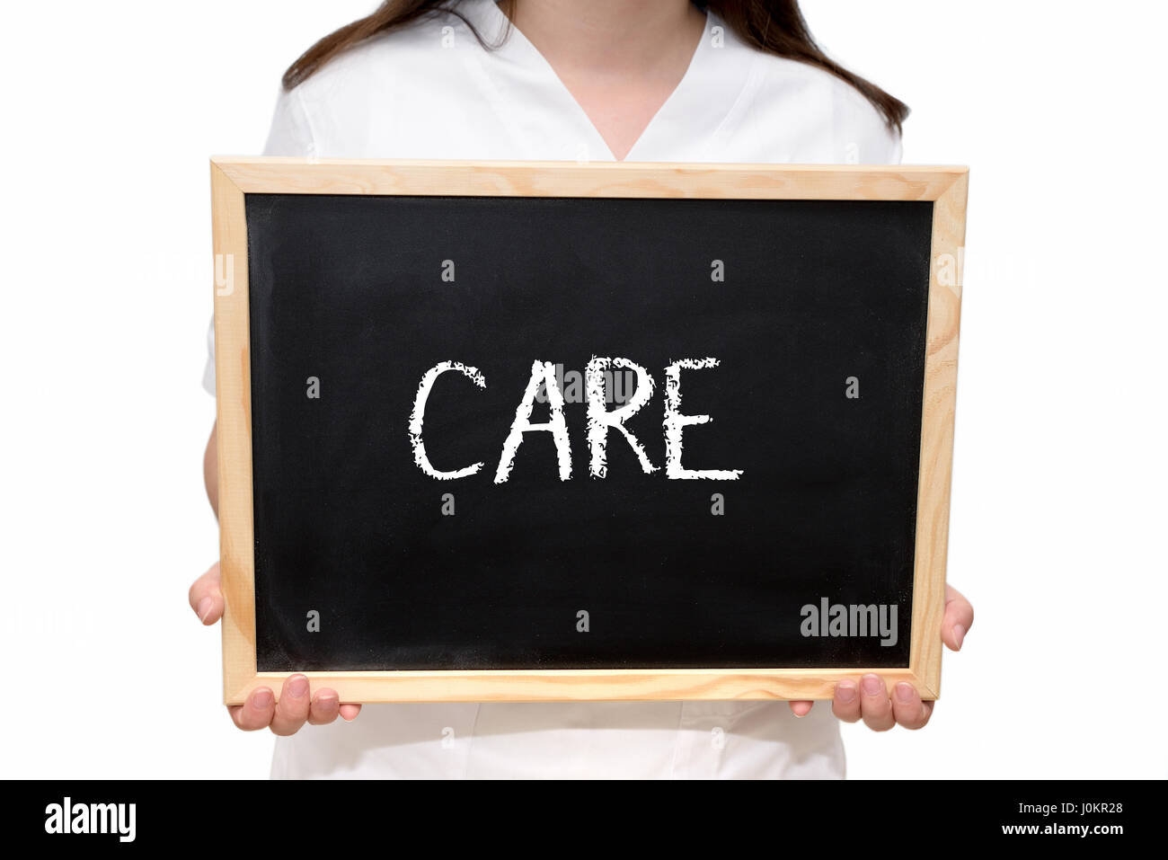 Female nurse holding a slate board with the text Care written with chalk, isolated on white background. Stock Photo
