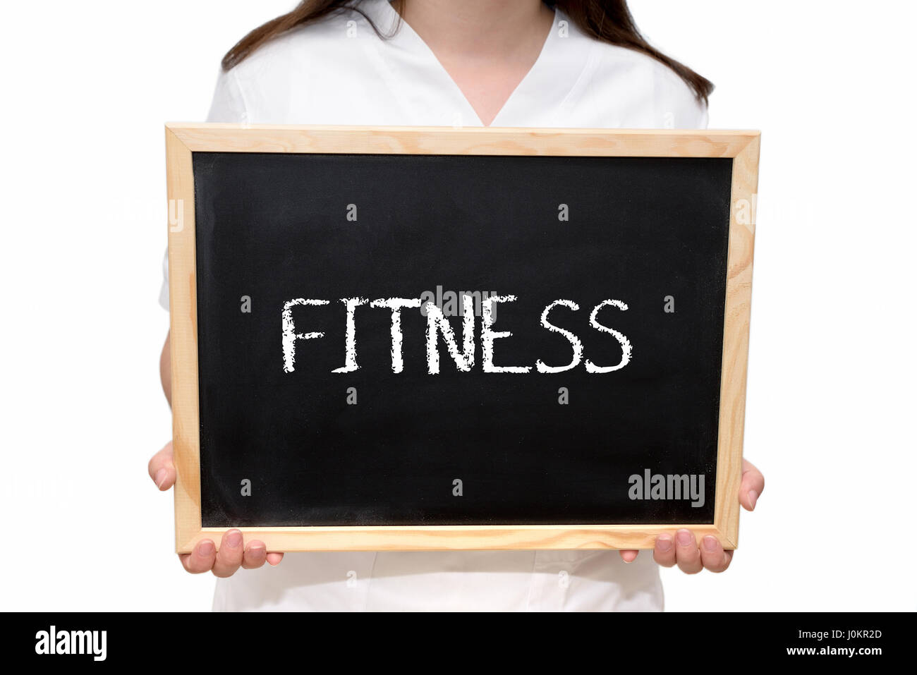Female nurse holding a slate board with the text Fitness written with chalk, isolated on white background. Stock Photo