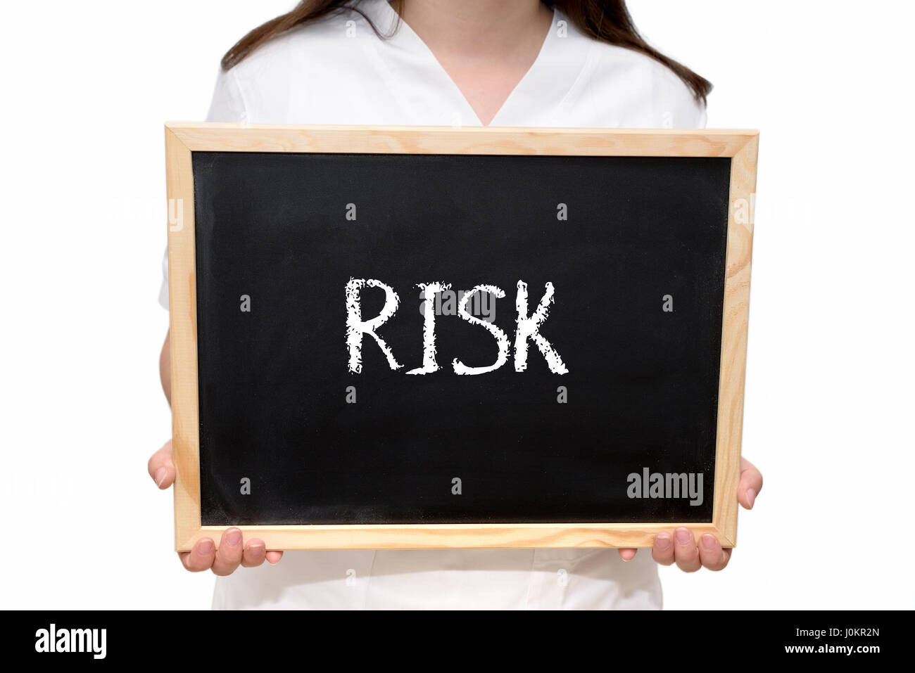 Female nurse holding a slate board with the text Risk written with chalk, isolated on white background. Stock Photo