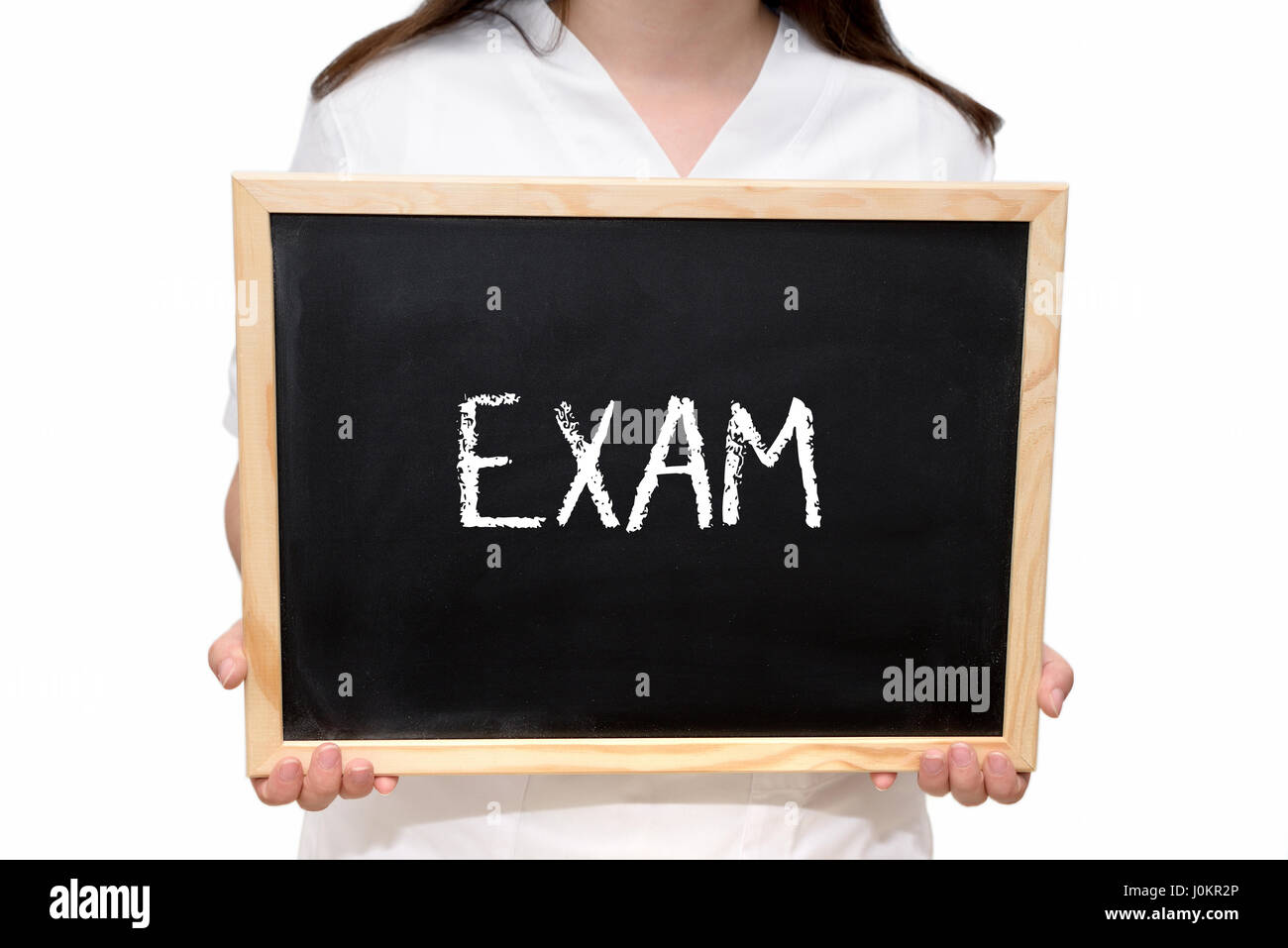 Female nurse holding a slate board with the text Exam written with chalk, isolated on white background. Stock Photo