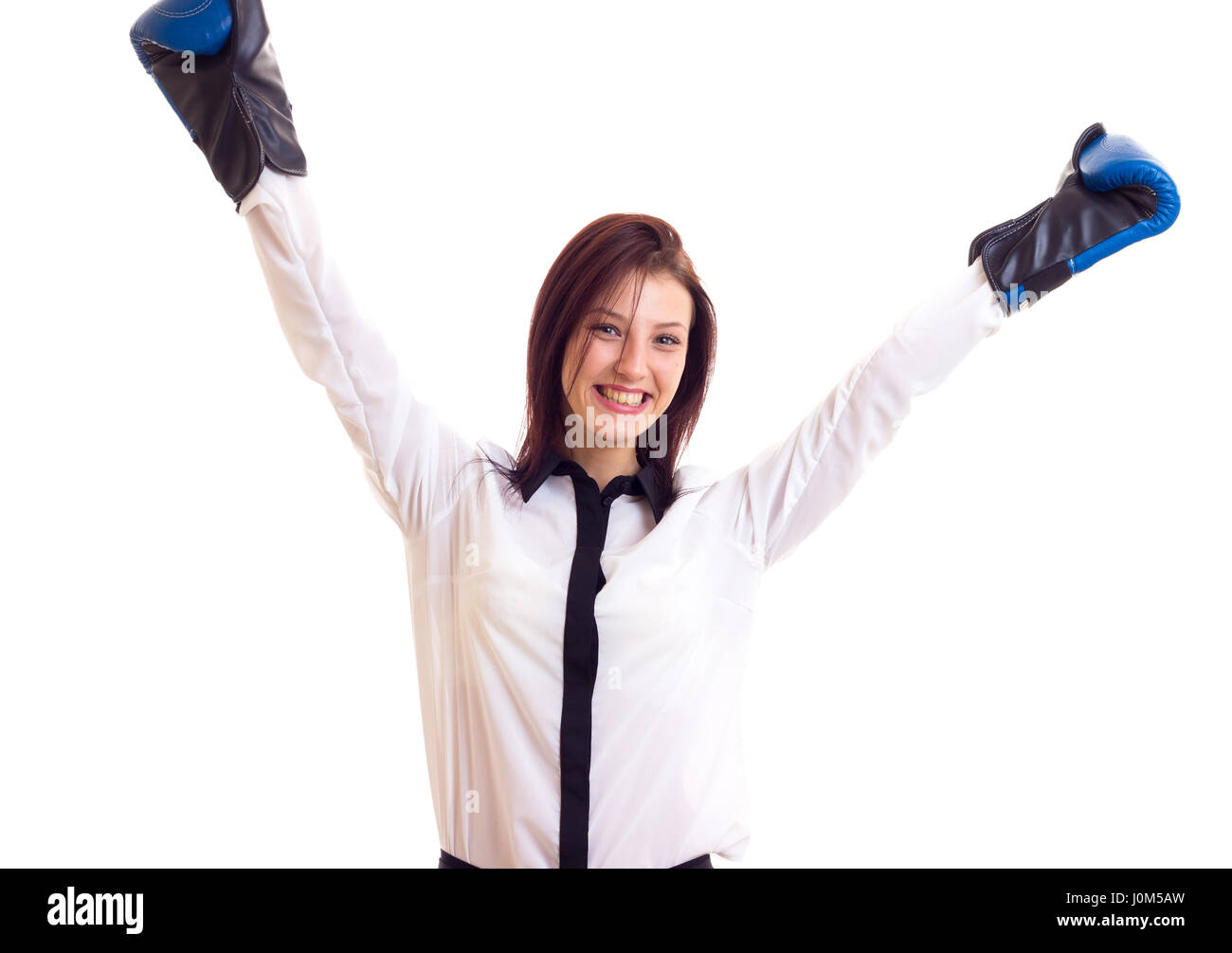 Smiling young woman in white shirt with dark hair and blue boxing gloves on white background in studio Stock Photo