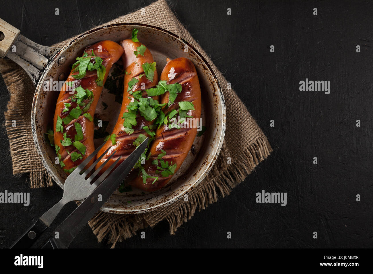 Fried sausage on an old pan on a black background Stock Photo