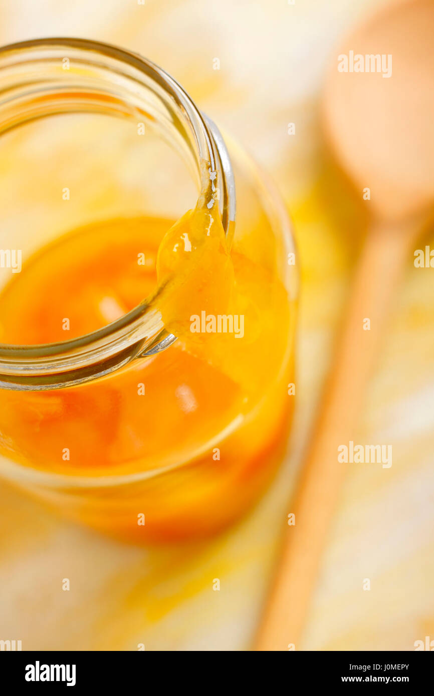 Yellow mirabelle plum jam blob over opened jar screw filled with jam. Shallow depth of field. Stock Photo
