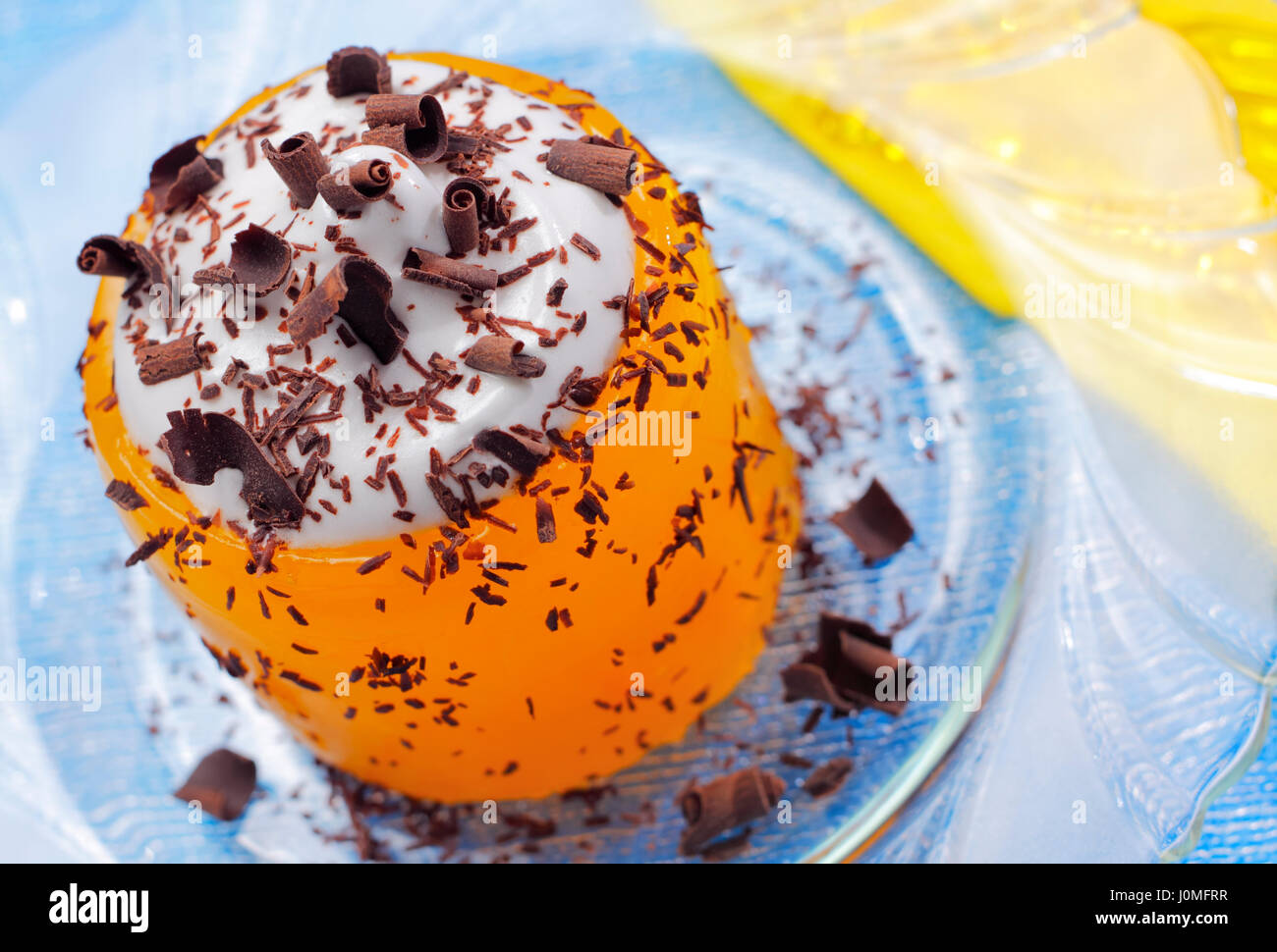 Pumpkin jelly with whipped cream and chocolate curls. Focus on whipped cream with chocolate garnish. Stock Photo
