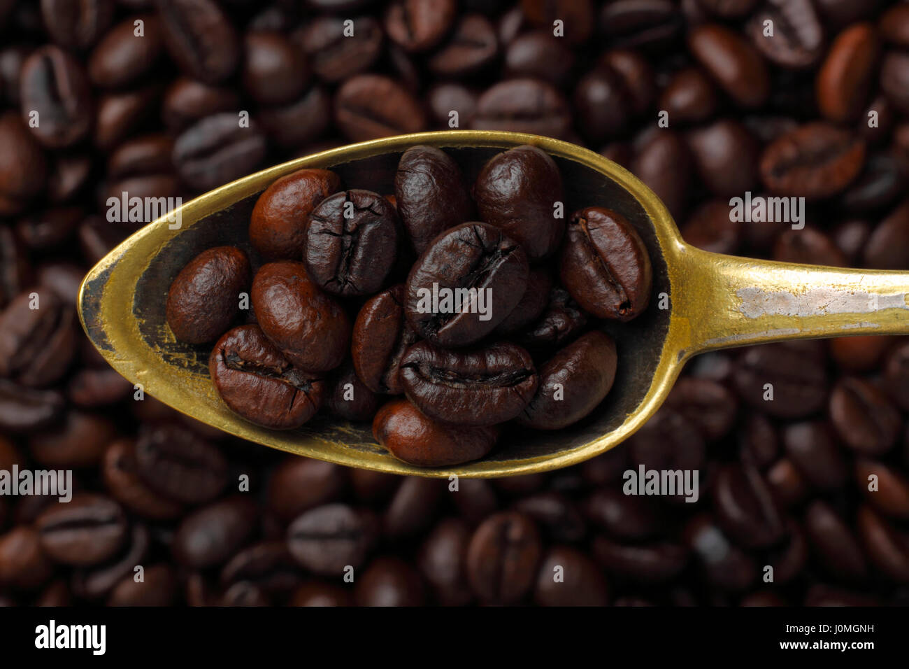 Aged spoon filled with coffee grains (Robusta coffee). Close-up, top view. Stock Photo