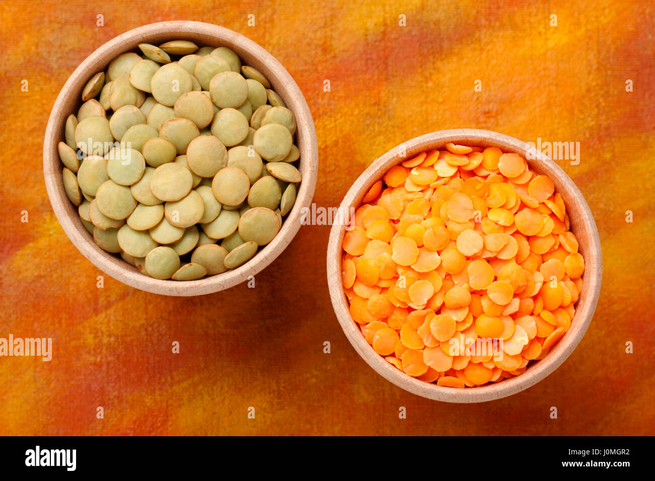 Top view of two wooden bowls with green and red lentils (Lens culinaris
