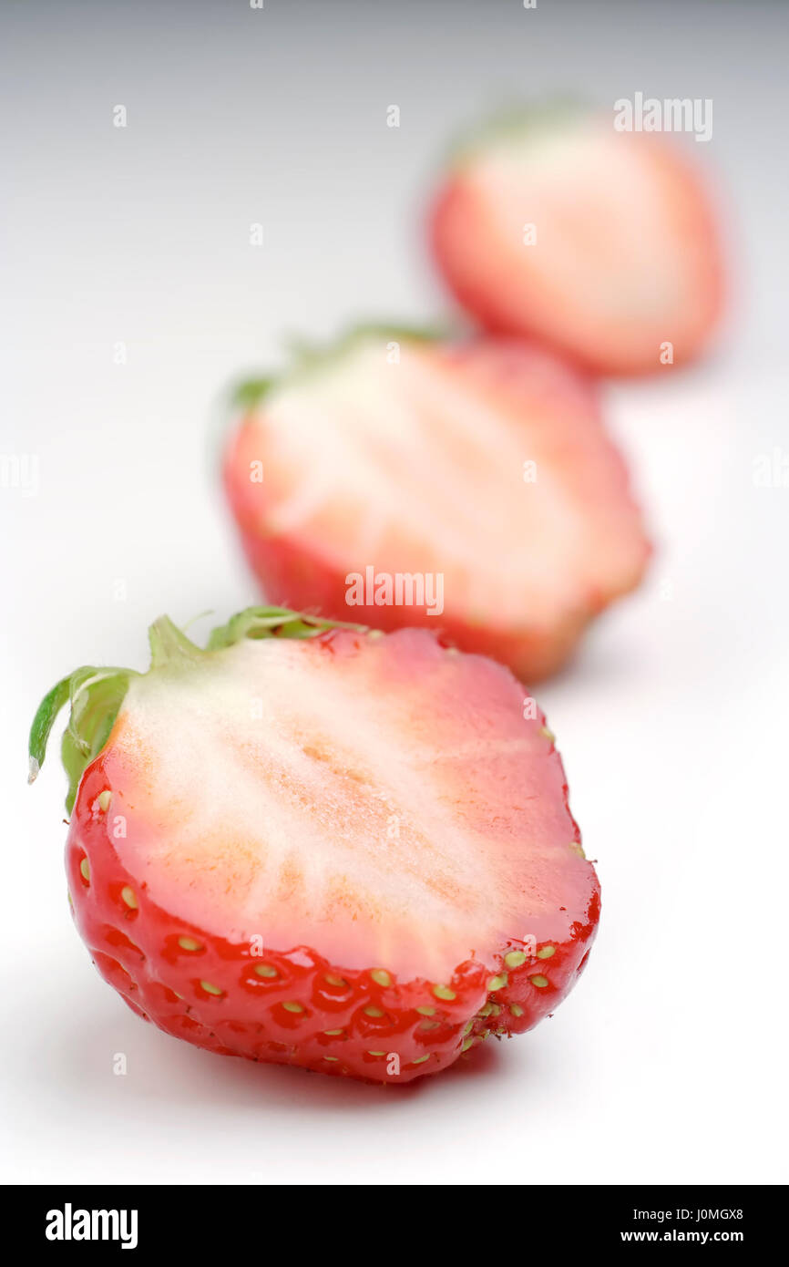 Garden strawberry (Fragaria × ananassa) on light background; focus on first half strawberry. Stock Photo