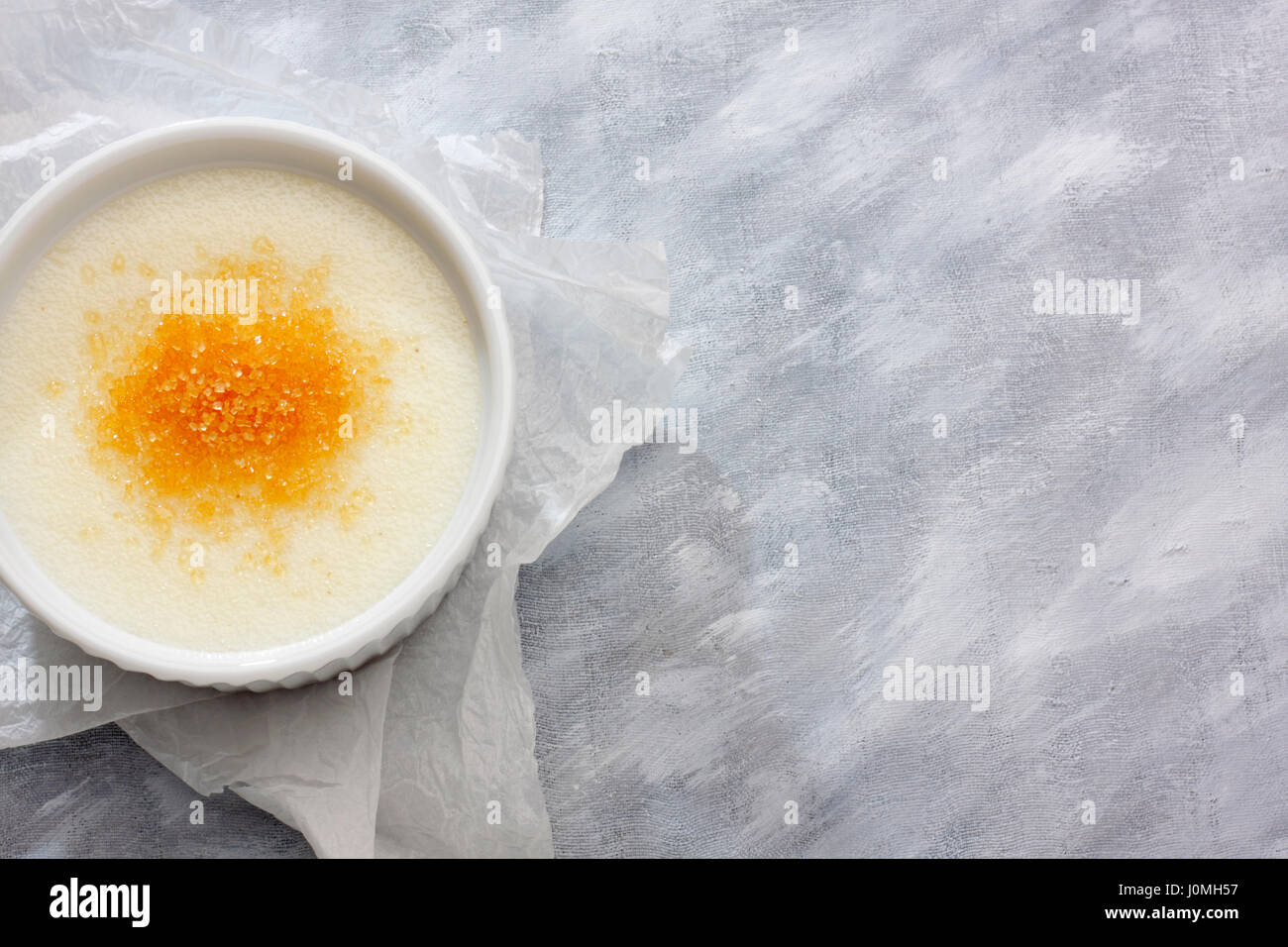 Wheat semolina (farina) with milk and brown cane sugar in a ceramic bowl on paper cloth. View from above. Stock Photo