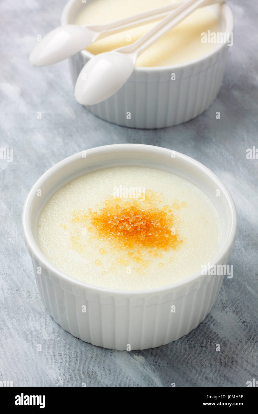 Ramekins filled by wheat semolina (farina) with milk and brown cane sugar.  Focus on first ramekin Stock Photo - Alamy