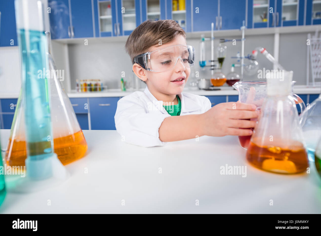 Little boy in protective glasses making experiment in chemical ...