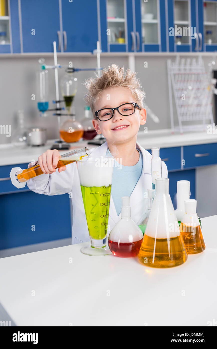 Smiling little boy in eyeglasses making experiment in chemical lab