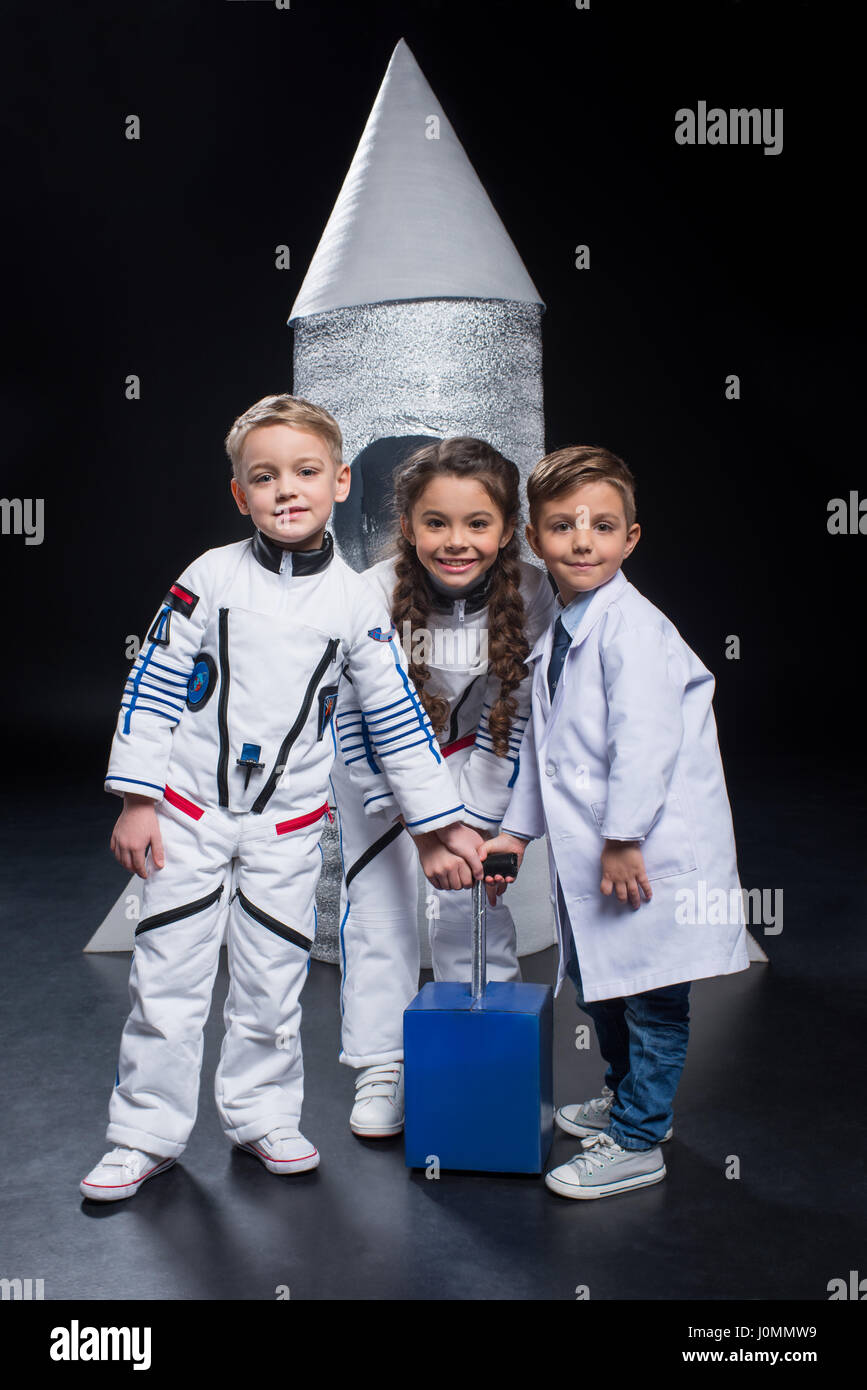 Three smiling little kids playing astronauts and launching rocket Stock Photo
