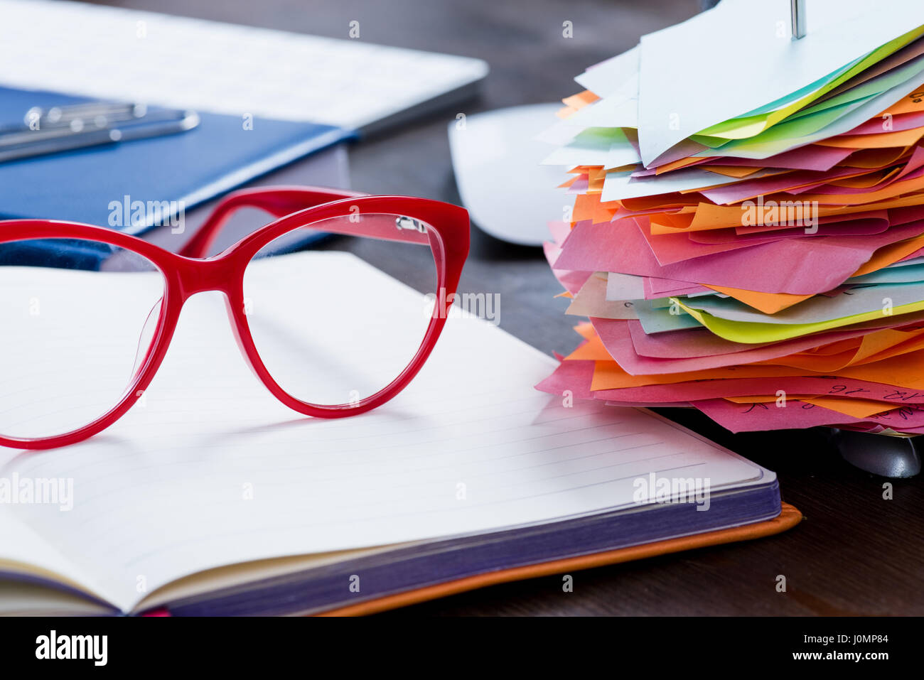 Close-up view of red eyeglasses on open notebook and office supplies at workplace Stock Photo