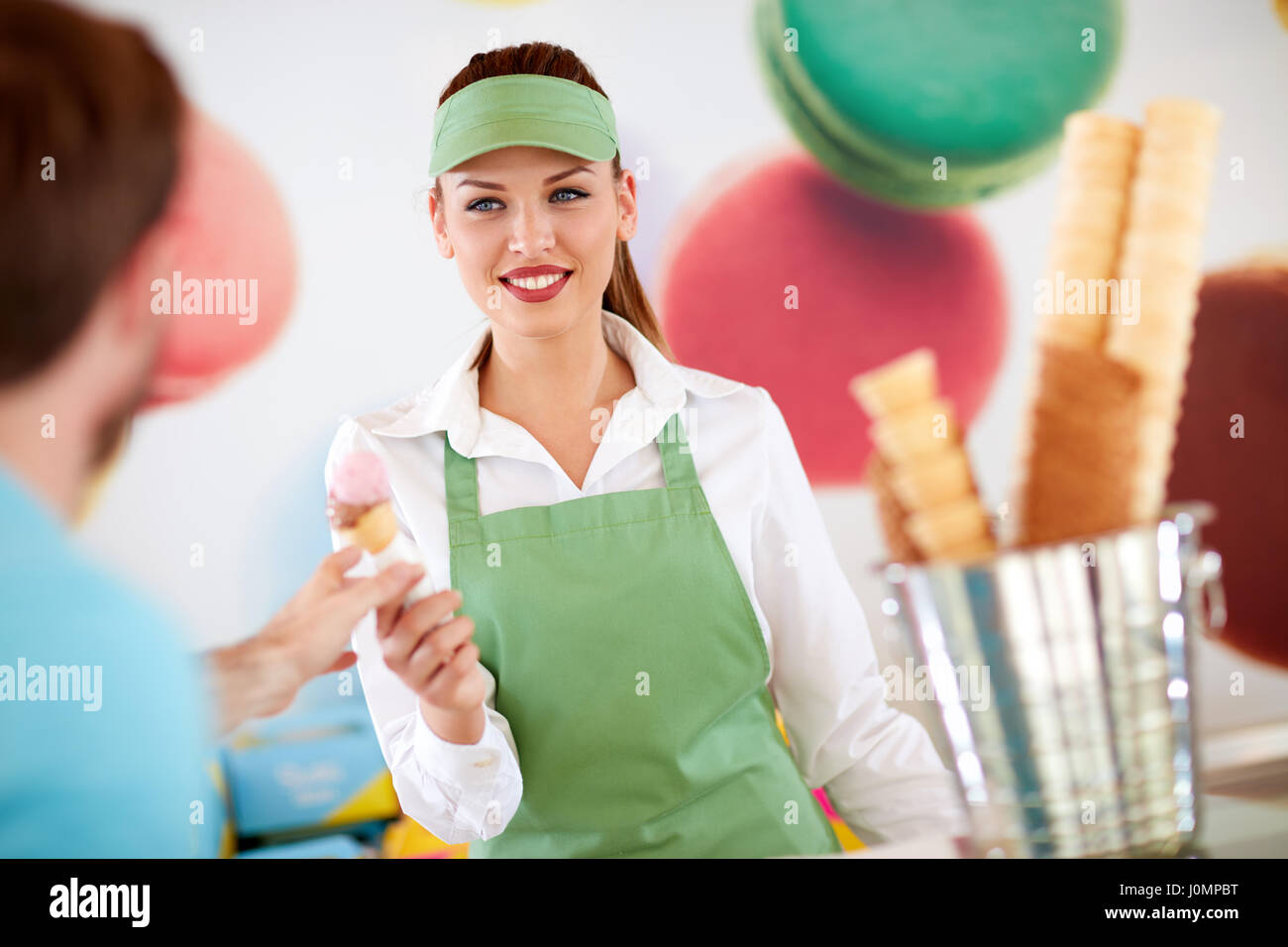 Beautiful female worker in confectionery giving ice cream to customer ...