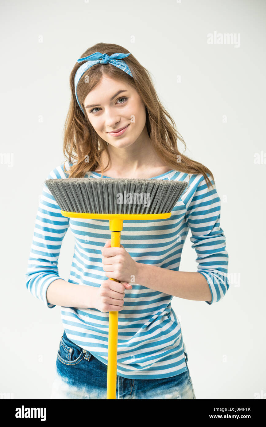 Attractive young woman holding broom and smiling at camera Stock Photo