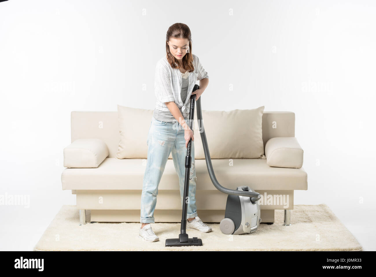 Concentrated beautiful young woman using vacuum cleaner Stock Photo - Alamy