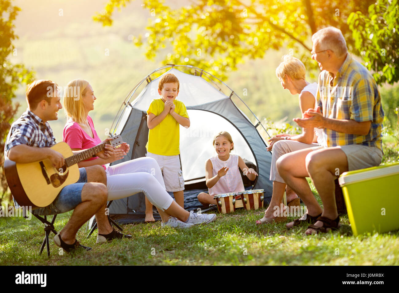 Generation family playing a guitar and singing on camping Stock Photo