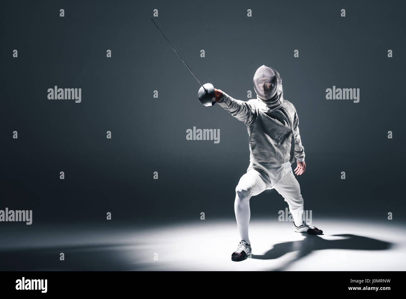 Professional fencer in fencing mask with rapier standing in position on